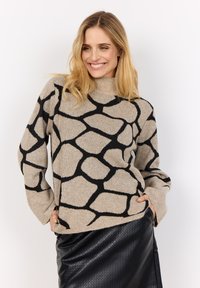 Beiger Strickpullover mit schwarzem geometrischem Muster, mit hohem Kragen und breiten Ärmeln. Die Textur wirkt weich und gemütlich.