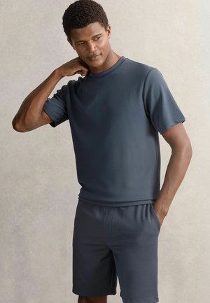 Tricou sportiv gri închis, cu mâneci scurte și material texturat, asociat cu pantaloni scurți asortați. Ambele au o croială lejeră și talie elastică.