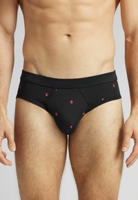 Czarne bawełniane majtki w dopasowanym kroju z małymi wzorami biedronek w kolorze czerwonym. Gładka faktura z mocną gumką w talii.