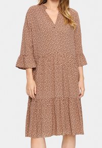 Robe midi marron à pois noirs, décolleté en V, manches évasées et jupe à volants. Fabriquée dans un tissu léger avec une texture fluide.