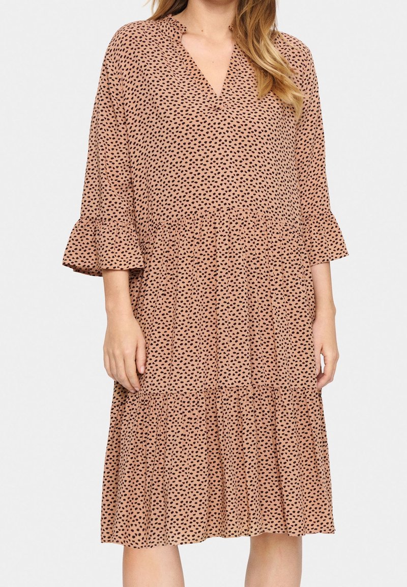 Robe midi marron à pois noirs, décolleté en V, manches évasées et jupe à volants. Fabriquée dans un tissu léger avec une texture fluide.