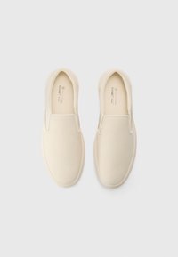 Slip-on kanvas sko i off-white med en glat tekstur, minimalistisk design, elastiske sidepaneler og en rund tåform.