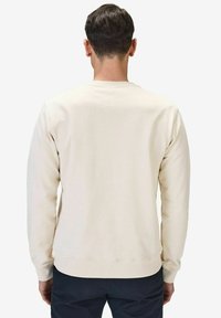 Crewneck sweatshirt i ljusbeige, tillverkad av en mjuk bomullsblandning. Har långa ärmar och ribbade muddar och fåll. Minimalistisk design.