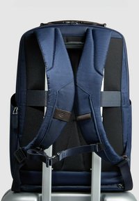 Marineblauer Rucksack mit gepolsterten, konturierten Trägern. Strukturierter Stoff und Mesh-Einsätze für Atmungsaktivität. Reißverschlusstaschen und verstellbare Riemen.