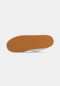 Semelle de chaussure en caoutchouc marron avec un motif en grille et un petit bloc logo rectangulaire au centre.
