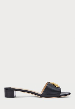 Black leather slide sandal with a low block heel, featuring a gold-tone hardware accent and an open-toe design. Smooth texture throughout.
