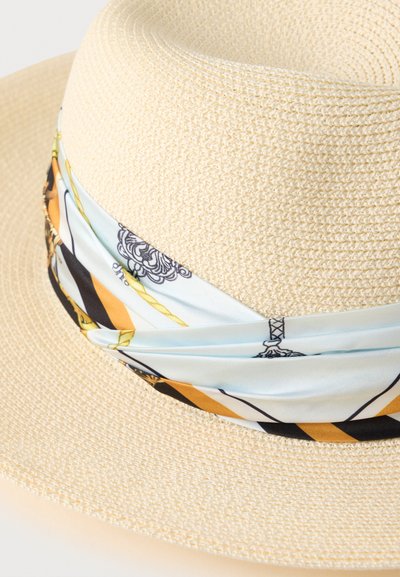 Ψάθινο καπέλο με φαρδύ γείσο, που διαθέτει φάσα από σατέν με σχέδιο σε ανοιχτό μπλε, μαύρο και χρυσό χρώμα, τυλιγμένη γύρω από το στέμμα. Υφασμένη ψάθινη επιφάνεια.