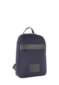 Mornarsko modra nahrbtnik iz mehke tkanine z elegantnim dizajnom, usnjenimi poudarki, ročajem na vrhu in logotipom na dnu spredaj. Zapira se z zadrgo.
