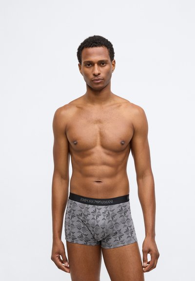 Γκρι μποξεράκια με μαύρο γεωμετρικό σχέδιο, μαύρη ζώνη που αναγράφει "EMPORIO ARMANI," φτιαγμένα από ελαστικό βαμβάκι για άνεση.