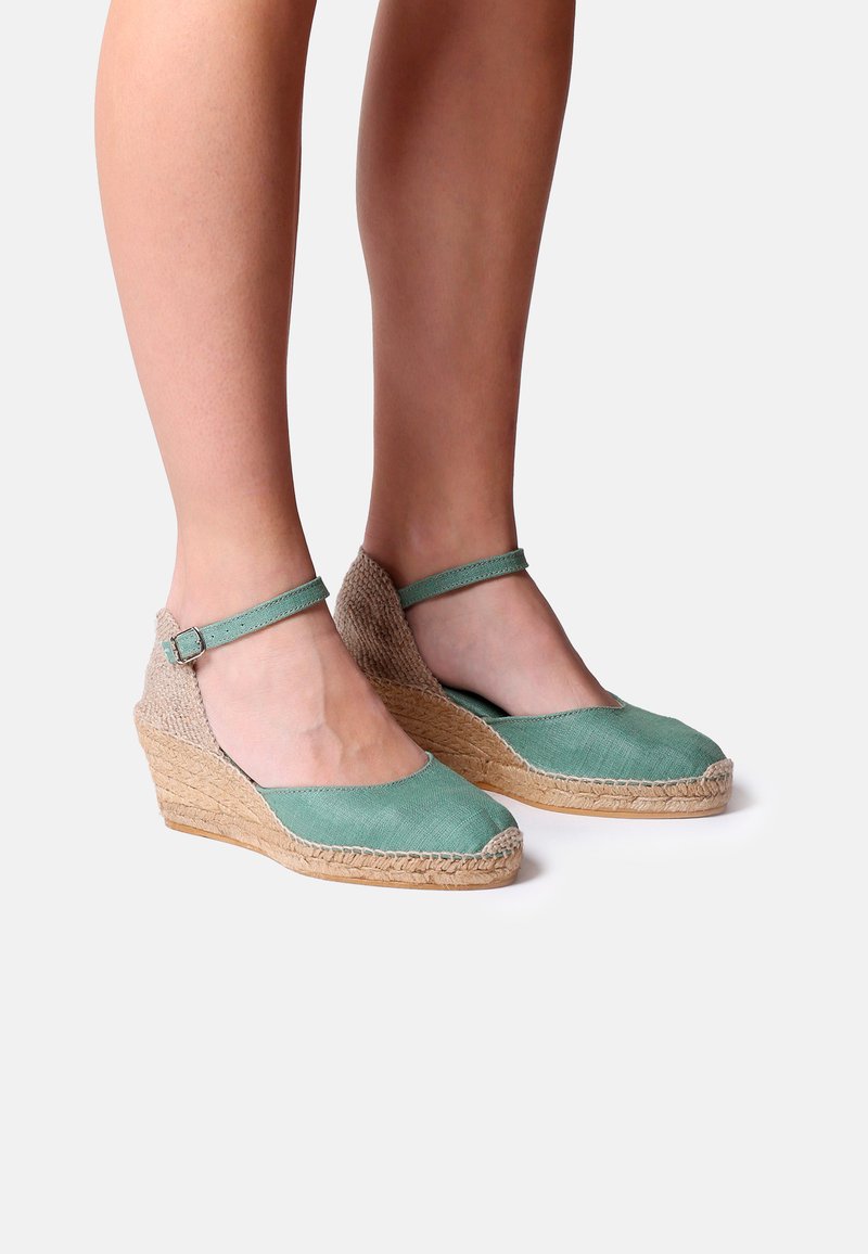 Žalios wedge espadrilės su tekstūruotu jūtos padu ir kulkšnies dirželiu. Viršus pasižymi lygaus audinio apdaila šviesiai mėtų atspalvyje.