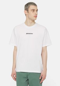 White short-sleeve t-shirt with a round neck featuring a black "Dickies" logo printed at the center. Made of cotton, lightweight material.