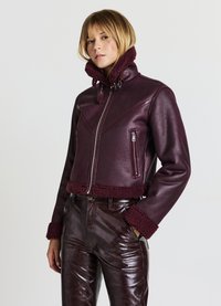 Veste en cuir bourgogne avec col et poignets en shearling doux, design ajusté, poches zippées horizontales et finition texturée.