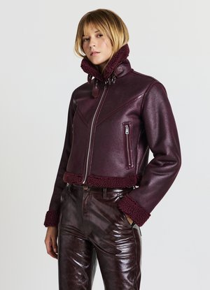 Giacca in pelle bordeaux con colletto e polsini in pelliccia morbida, design aderente, tasche con zip orizzontali e finitura testurizzata.