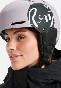 Kask narciarski Roxy w miękkim różowym kolorze z czarnymi akcentami. Posiada okrągłą grafikę, otwory wentylacyjne oraz regulowane paski zapewniające pewne dopasowanie.