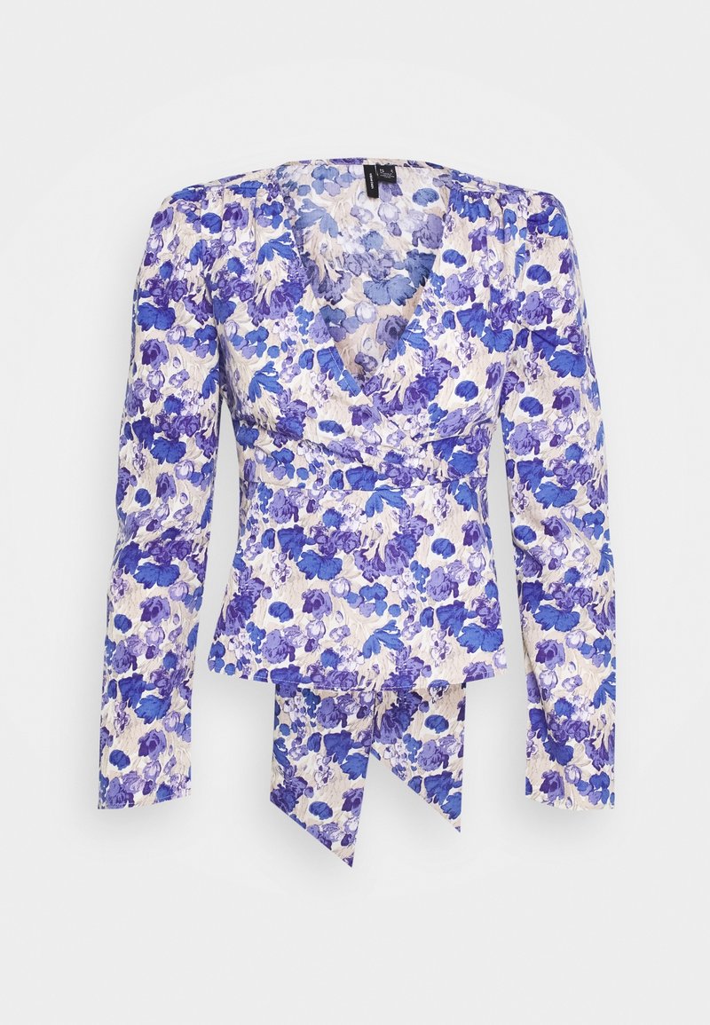 Blusa avvolgente floreale in tessuto bianco con motivi di fiori blu e viola. Presenta maniche lunghe a palloncino e scollatura a V. Dettaglio decorativo con fiocco sull'orlo.