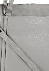 Grijze leren handtas met een gestructureerd oppervlak, voorzien van een dunne schouderriem en zilverkleurige accenten. Minimalistisch design met strakke lijnen.