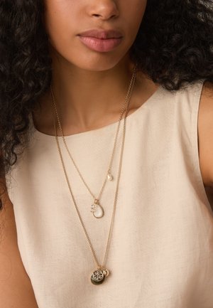 Goldfarbene, geschichtete Halsketten mit einem tropfenförmigen Anhänger mit Edelstein, einer kleinen Perle und einem runden Anhänger mit filigranen Details.