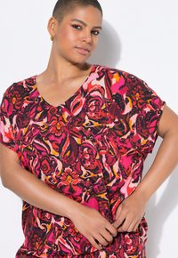 Top a maniche corte con scollatura a V in un vivace motivo floreale con toni di rosa, rosso e arancione su uno sfondo scuro, realizzato in tessuto morbido.