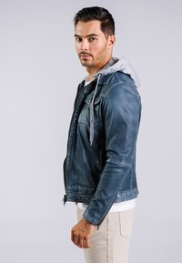 Blaue Lederjacke mit grauem Kapuzenhoodie, Reißverschluss und zwei Fronttaschen. Verfügt über eine abgenutzte Textur und eine taillierte Passform.