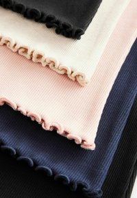 Ribbet stofprøver i sort, marineblå, lyserød og creme med bølgede kanter. Hver prøve har en distinkt farve og tekstur.