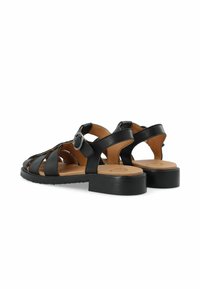 Sandalias negras de cuero con tacón cerrado, puntera abierta, diseño de correas y detalle de hebilla redonda en el lateral. Suela plana con ligera elevación.