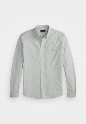 Chemise à manches longues boutonnée avec fines rayures verticales vertes et un petit logo brodé sur la poitrine gauche.