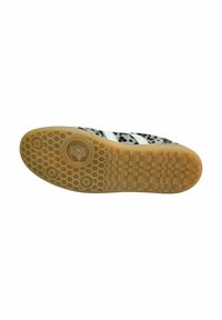 Suela de una zapatilla que presenta un patrón de panal. La parte inferior es marrón con acentos circulares y textura de rejilla; la parte superior tiene un diseño en blanco y negro.