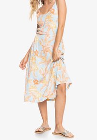 Kukkakuvioinen mekko vaaleansinisellä taustalla, jossa on oransseja ja keltaisia kukkia, rento istuvuus ja polvipituinen helma.