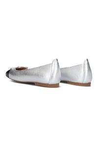 Zilveren ballerina's met een zwarte neuskap, een gladde metallic textuur, een ronde vorm en een klein strikje aan de voorkant. Bruine zool.