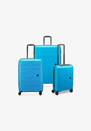 Drei blaue Hartschalenkoffer in unterschiedlichen Größen. Das Design verfügt über horizontale Rillen, ausziehbare schwarze Griffe und multidirektionale Räder.