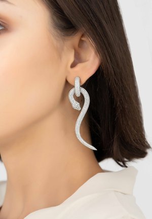 Silver snake-shaped earring, featuring a sparkling texture with a loop detail. Curved design extends downwards, ending in a pointed tip.