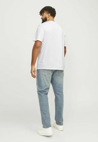 Hvit bomull t-skjorte med korte ermer, kombinert med lys blå denimjeans. Antrekket er fullført med hvite sneakers.