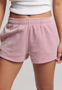 Pantalones cortos de algodón rosa con cintura elástica, que presentan un logo bordado minimalista y una textura suave, cortados por encima de la mitad del muslo.