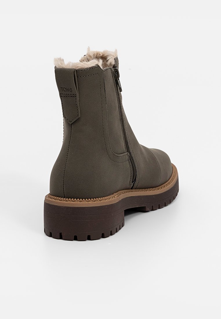 Olijfgroene enkellaars met faux fur voering, zijrits en bruine rubberen zool met gestructureerde loopvlak voor grip.