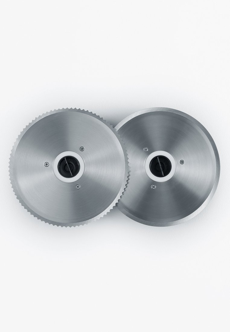 Due ingranaggi metallici circolari con superfici lisce, bordi seghettati e fori centrali, che riflettono la luce su uno sfondo bianco.