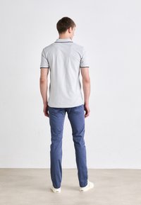 Camisa polo gris con ribete negro y pantalones sólidos azules. El conjunto presenta un corte clásico y un diseño limpio, adecuado para ropa informal.