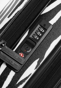 Hartschalenkoffer im schwarz-weißen Zebra-Muster mit einem TSA-zugelassenen Kombinationsschloss, doppelten Reißverschlüssen und einer strukturierten Oberfläche für besseren Halt.