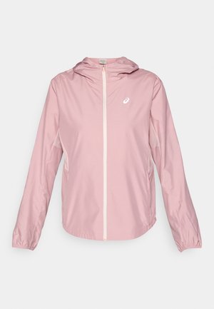 Veste légère rose pâle avec capuche, fermeture éclair complète à l'avant et poignets élastiques. Présente un petit logo sur la poitrine et une texture lisse.