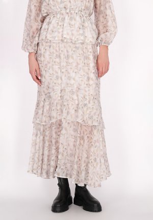 Blumenkleid mit schichtweisem Design, aus sanftem, pastellfarbenem Stoff, mit Rüschendetails und langen Ärmeln. Kombiniert mit schwarzen klobigen Stiefeln.