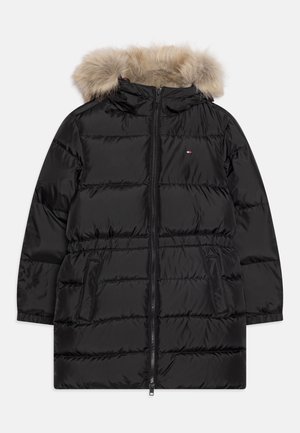 Veste rembourrée noire avec une capuche en fourrure, fermeture éclair et poches latérales. Présente un design matelassé horizontal et un petit détail de logo.