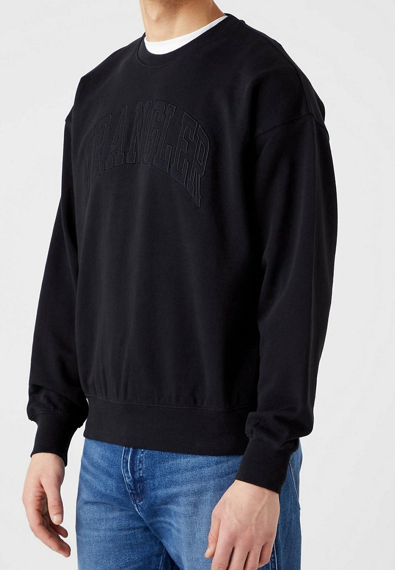 Felpa nera con colletto a girocollo e maniche lunghe, caratterizzata da un logo "Wrangler" in rilievo sulla parte anteriore. Tessuto morbido, vestibilità comoda.