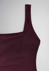 Dark purple sleeveless top with a square neckline and wide shoulder strap, shown against a light gray background.