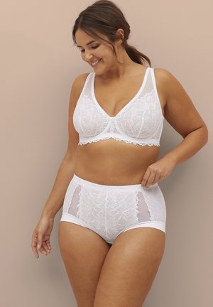 Weißer Spitzen-BH mit breiten Trägern und Unterdraht, kombiniert mit hochgeschnittenen Spitzen-Slips, die durchscheinende Einsätze haben. Beide haben florale Muster.