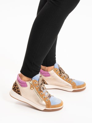 Füße in mehrfarbigen High-Top-Sneakers mit pastellblauen, braunen, rosa und Leopardenmuster-Akzenten, kombiniert mit schwarzen eng anliegenden Hosen.