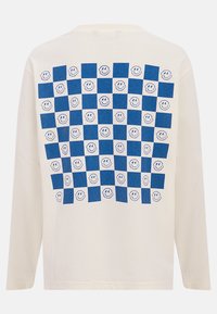 Biała koszulka z długim rękawem, z niebiesko-białą kratą i grafiką uśmiechniętego emotikona na plecach. Miękka tkanina, luźny krój.