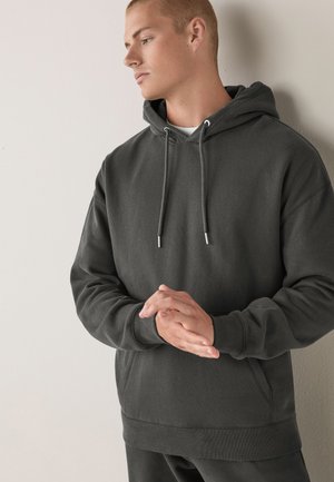 Donkergrijze hoodie gemaakt van zachte stof, met een buidelzak en een koord met metalen punten; ontspannen pasvorm.