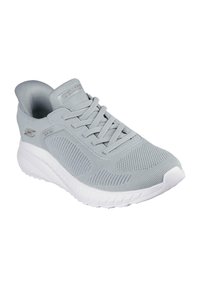 Scarpa sportiva grigia chiara con tomaia in rete, design con lacci, collare imbottito e suola in gomma bianca con dettagli testurizzati.