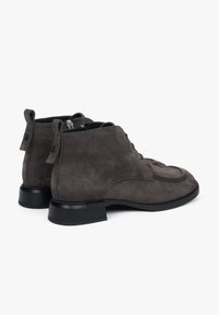 Szare zamszowe botki za kostkę z okrągłym noskiem, sznurowanym przodem i czarną gumową podeszwą. Posiadają tylną pętelkę i subtelne detale przeszycia.