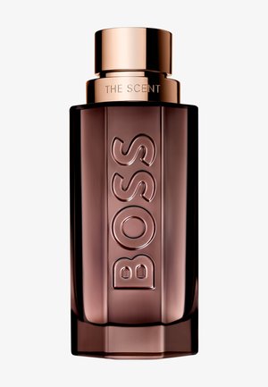 Rechthoekige bruine glazen fles met gegraveerde "BOSS" tekst en glanzende roségouden dop met het label "THE SCENT".