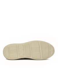 Suela de zapato con un material texturizado de color beige claro. Presenta patrones geométricos y marca, diseñada para proporcionar agarre y estabilidad.